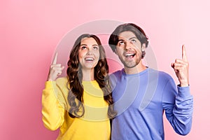 Photo of young couple happy positive smile look indicate fingers empty space promo suggest sale isolated over pink color