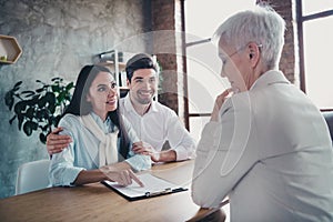 Photo of young couple hug point finger clipboard meeting realtor lady desk loft interior office indoors