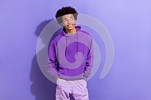 Photo of young dreaming man wearing sportswear hoodie hands pockets model minded look novelty isolated on purple color