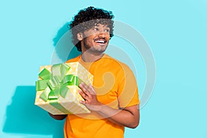 Photo of young dreamy student guy looking empty space holding package gift box desirable new year isolated on aquamarine
