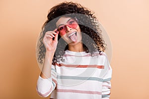 Photo of young excited crazy latin girl happy smile grimacing tongue out wear pink sunglass isolated over beige color