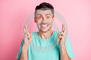 Photo of young excited man happy positive smile crossed fingers expect wish luck isolated over pink color background
