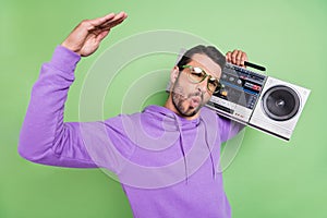 Photo of young excited man hold retro boombox music disco dance isolated over green color background