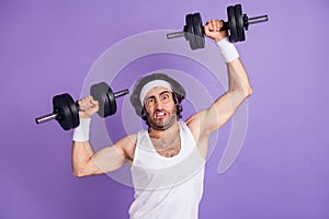 Photo of young funky funny crazy man in glasses lifting heavy dumbbell building muscles isolated on violet color photo