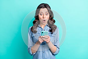 Photo of young girl amazed shocked look read browse fake news cellphone isolated over turquoise color background