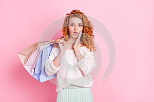 Photo of young girl amazed shocked surprised fake news hold bags shop isolated over pink color background