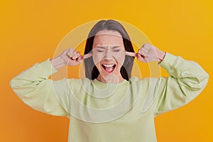 Photo of young girl cover fingers ears loud noise scream angry irritated isolated on yellow color background