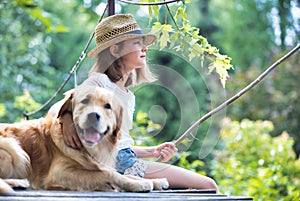 Young girl fishing while sitting with dog on pier