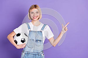 Photo of young girl happy positive smile hold soccer ball point finger empty space ad advise select isolated over violet