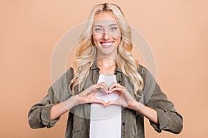 Photo of young girl happy positive smile show finger heart symbol love feelings  over beige color background