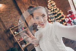 Photo of young girl happy positive smile show peace cool v-sign shoot selfie decor lights holiday winter evergreen tree