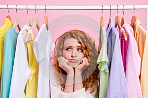 Photo of young girl unhappy upset dont now what to choose new collection clothes isolated over pastel color background