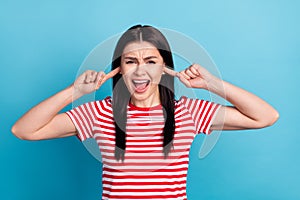 Photo of young girl unhappy upset irritated annoyed close fingers ears loud crazy isolated over blue color background