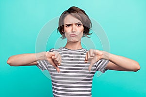 Photo of young girl unhappy upset show thumb-down bad quality dislike isolated over teal color background