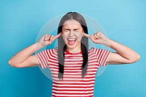 Photo of young girl unhappy upset stressed close fingers ears mad ignore avoid isolated over blue color background