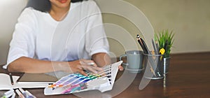 Photo of young graphic designer holding a stylus pen while selecting color from color guide.