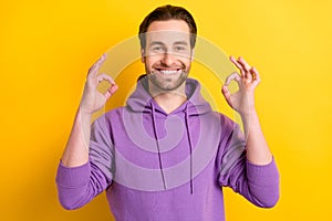 Photo of young guy happy positive smile show okay deal done cool recommend sign isolated over yellow color background