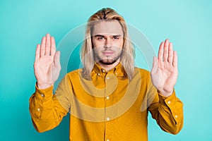 Photo of young guy show hands no stop sign denial rejection forbidden isolated over teal color background