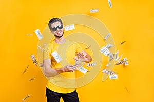Photo of young handsome careless guy throwing usa money banknotes away wealthy person wear sun specs casual t-shirt