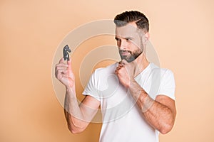 Photo of young handsome guy serious confident look on chess figure horse thoughtful isolated over beige color background