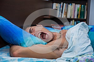 Photo of a young and handsome man asleep, scared with his mouth open in bed