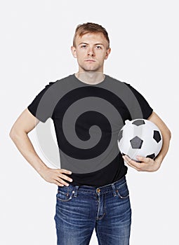 Portrait of a young handsome man in casual wear holding soccer ball over white background