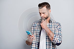 Photo of young handsome serious thoughtfuk minded man thinking hold cellphone isolated on grey color background