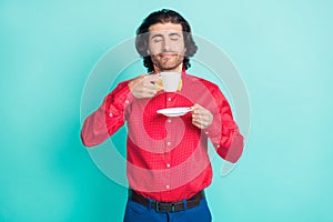 Photo of young handsome smiling dreamy man smell coffee having break relaxing isolated on turquoise color background