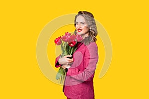 Photo of young happy business woman holding bouquet of tulips over yellow background