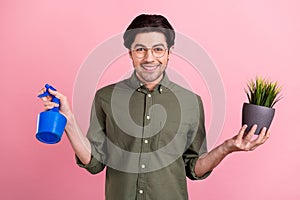 Photo of young happy positive cheerful man hold hands plant pulverizer water isolated on pink color background
