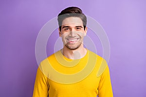 Photo of young happy positive good mood smiling cheerful man in yellow sweater isolated on violet color background