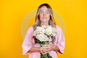 Photo of young happy positive woman hold hands smell flowers smile enjoy  on yellow color background