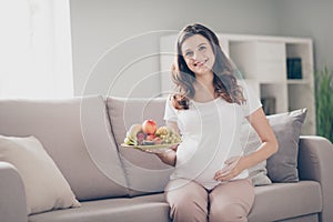 Photo of young happy woman mom hold fruit plate healthy food touch belly baby indoors home inside house