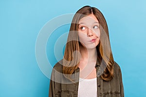 Photo of young hesitant small lady look blank space brainstorming displeased dislike isolated on blue color background