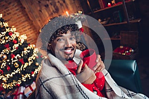 Photo of young homey positive satisfied man wear red sweater covered checkered blanket drinking tasty mulled wine