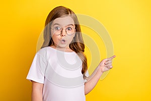 Photo of young little girl amazed shocked omg wow point finger empty space advertise direct isolated over yellow color