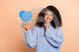 Photo of young lovely lady hand touch chin hold paper heart figure dreamy isolated over beige color background