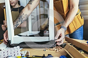 Photo of young male carpenter and his son working in workshop