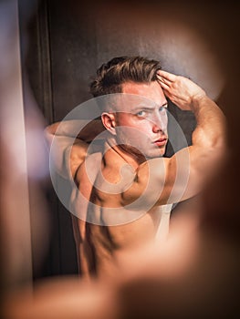 Photo of a young man admiring his muscular physique in the mirror