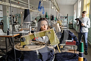 photo of a young man analysing a piece of work and a woman working with linking machine for knitting in textile industry