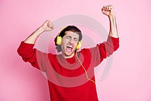 Photo of young man excited crazy have fun enjoy music earphones sing fists hands isolated over pink color background
