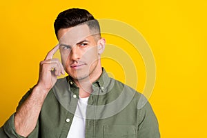 Photo of young man finger touch head think ponder look empty space isolated over yellow color background