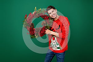 Photo of young man happy positive smile hold christmas wreath evergreen tree decoration new year isolated over green