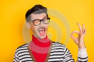 Photo of young man happy smile blink eye show okey sign deal done cool alright advert advise isolated over yellow color