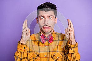 Photo of young man nervous worried crossed fingers hope wish luck fortune isolated over violet color background