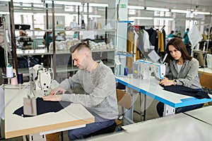 photo of a young man and other seamstresses sewing with sewing machine in a factory