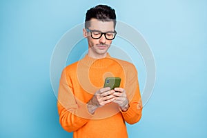 Photo of young man serious look read browse cellphone chat type sms isolated over blue color background