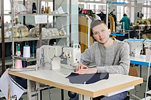 Photo of a young man sewing with sewing machine in a factory