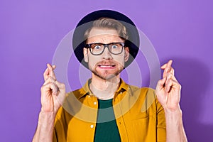 Photo of young man unhappy upset nervous worried crossed fingers hope wish luck isolated over violet color background