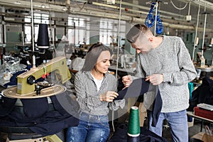 Photo of a young man and a woman analysing the work at the linking machine for knitting in textile industry